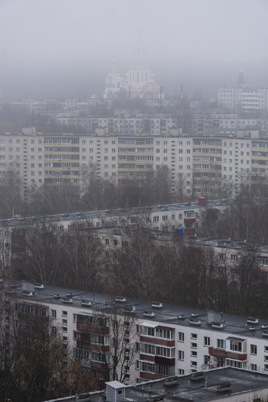 Жилые дома, церковь и туманный городской …